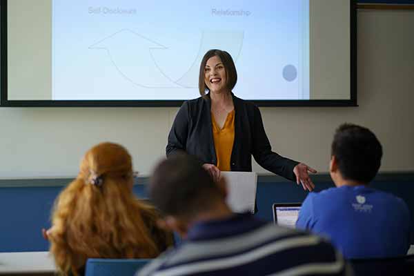 A female professor speaks to a classroom full of students.