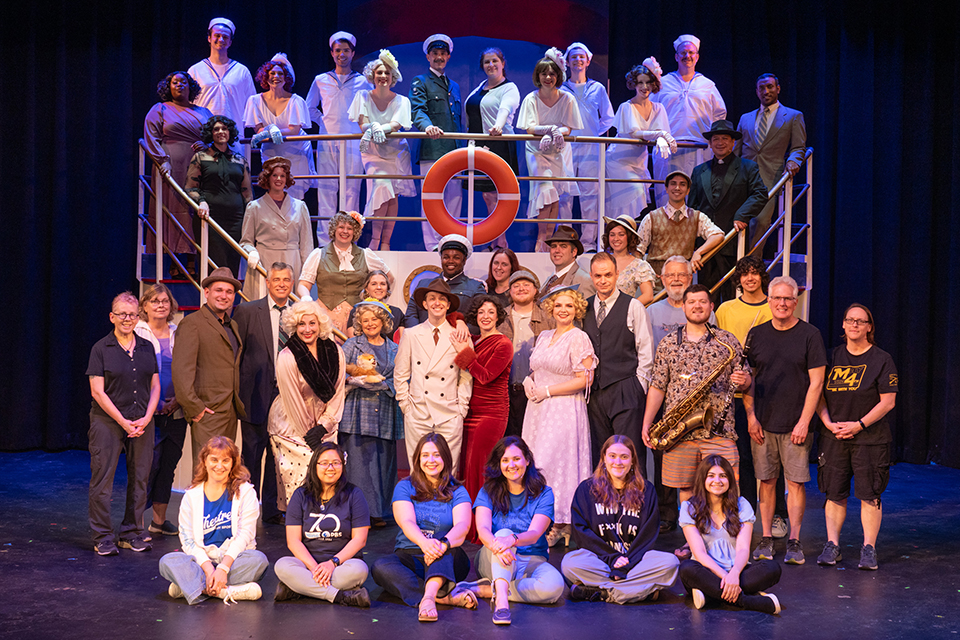 A large group of people pose on a set ship