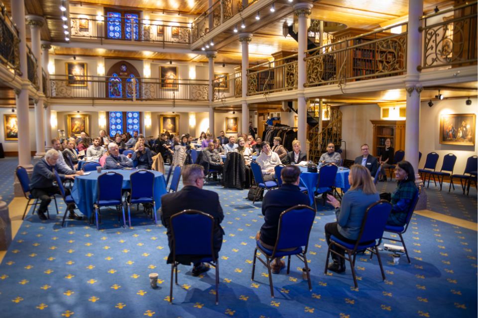 a woman in the middle of a row of people speaks to a large crowd of people