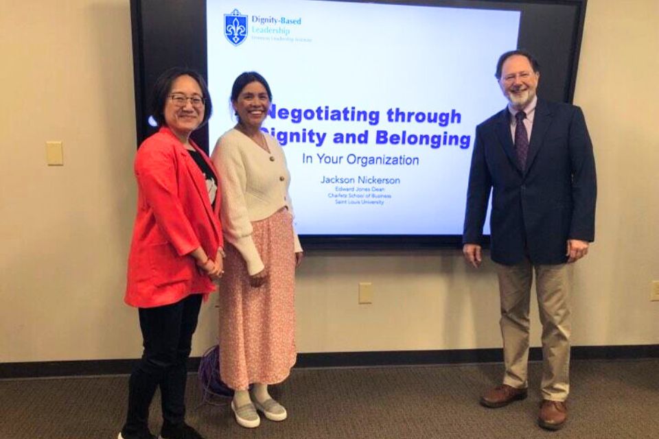 three people stand posed for a photo in front of a screen