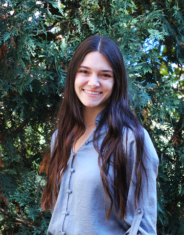 Mackenzie Poole crosses her arms and smiles for the camera outside of Cook Hall