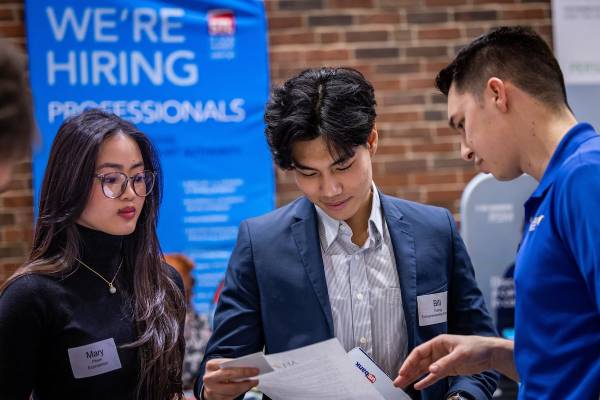 Two students with SLU Business School rep having a conversation about paperwork