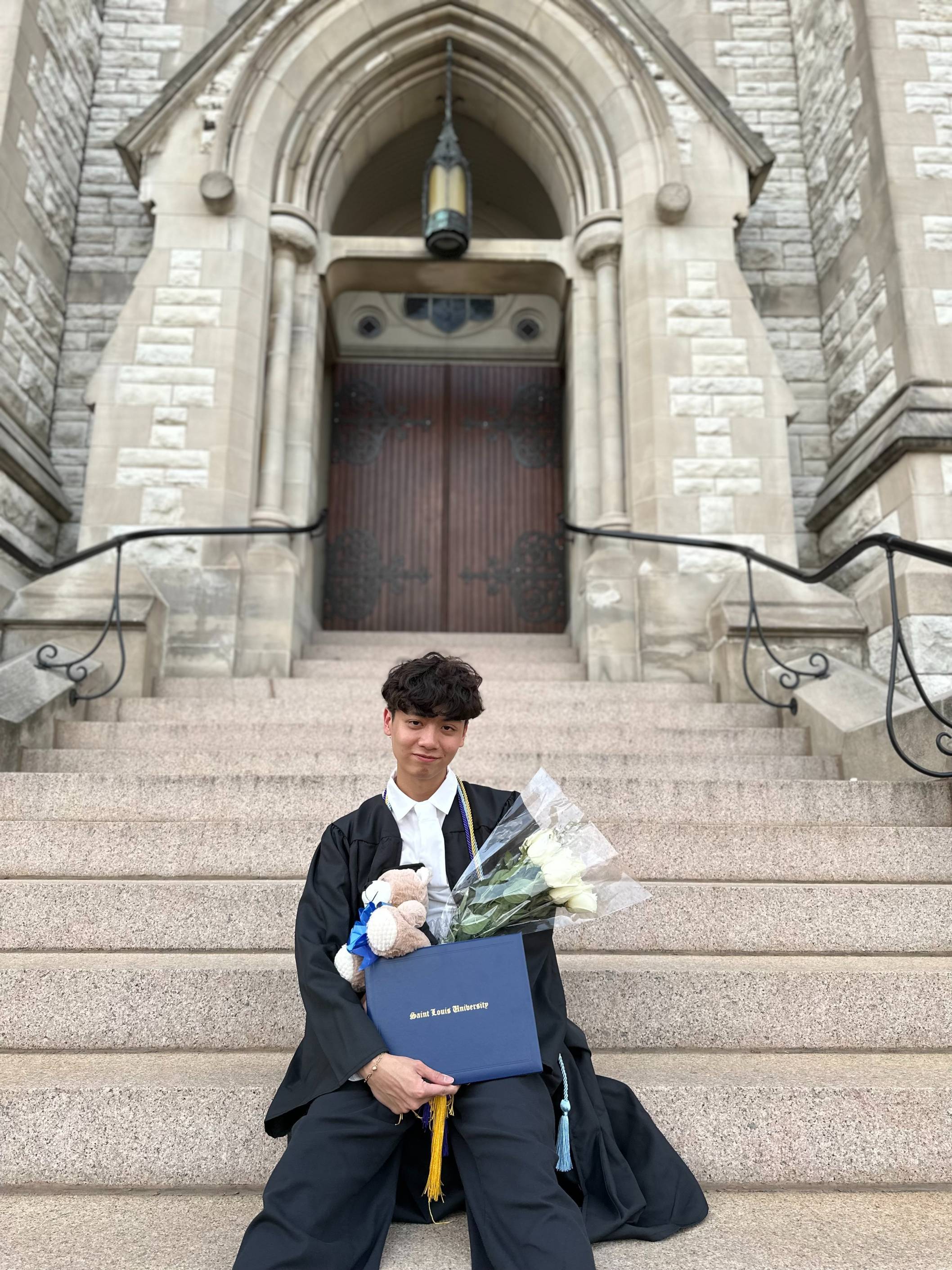 male with dark features holding a diploma