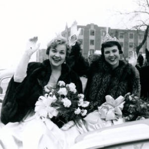 The women of the Saint Louis University Homecoming Court ride in a car and wave during the Homecoming Parade. (1955)